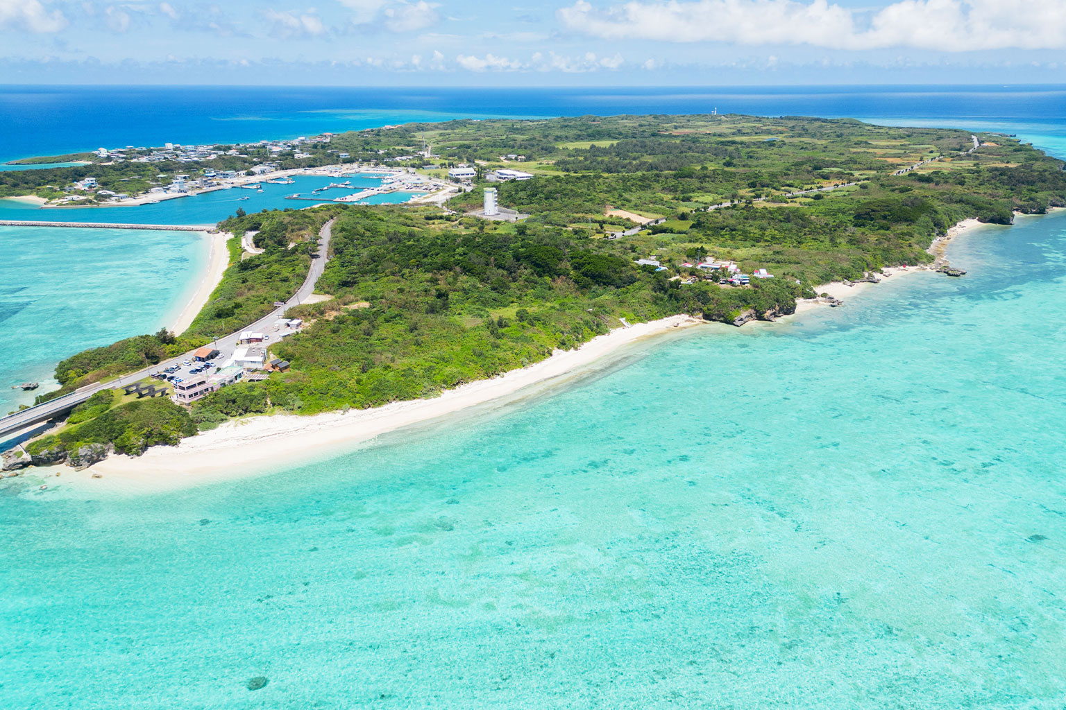 宮古島の代表的な絶景ポイントを俯瞰した美しい航空写真。青い海、白い砂浜、緑の島影が調和した全景
