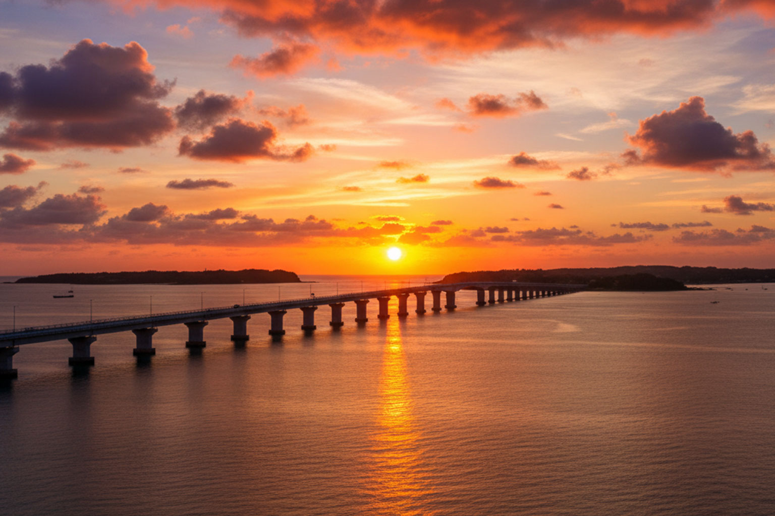 来間大橋から見える夕陽が海と空を黄金色に染める光景。橋のシルエットと黄金の水面
